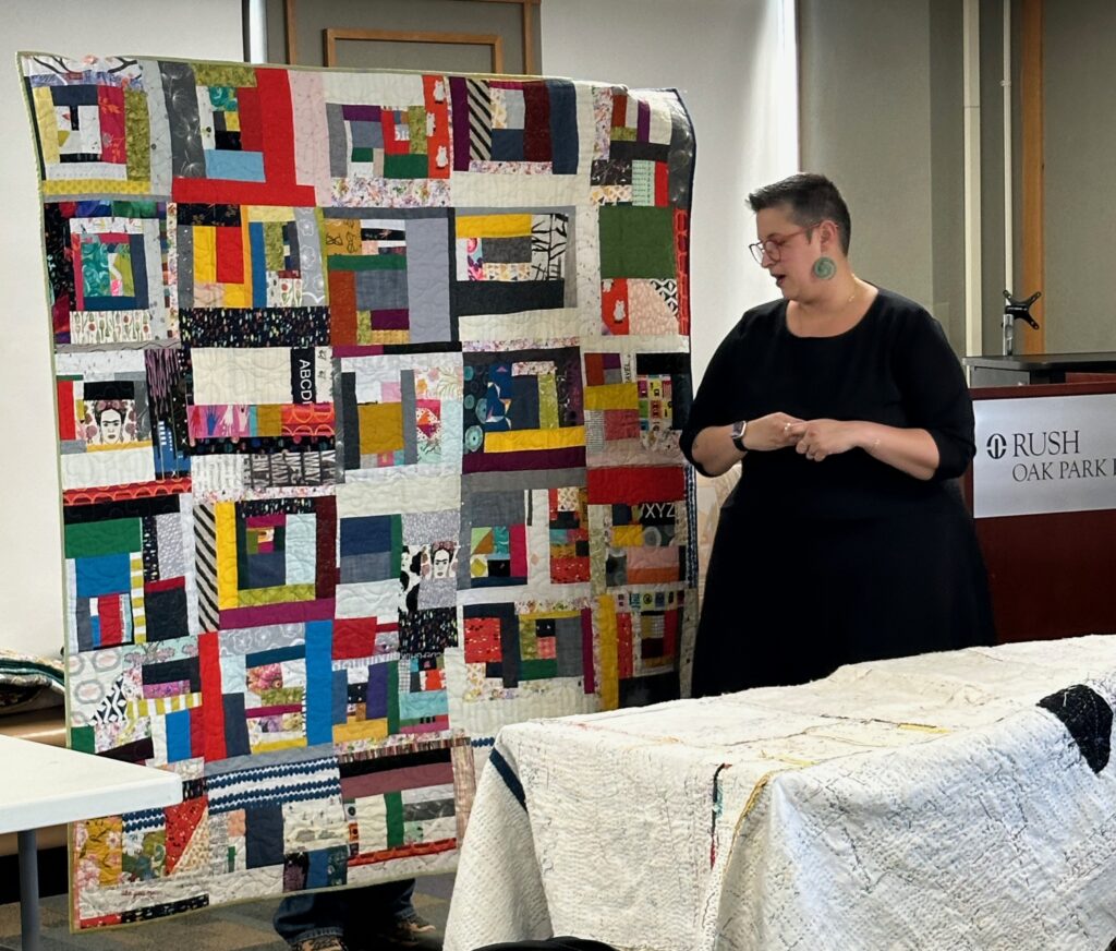 Quilter Maday Delgado shows off a colorful, scrappy quilt.
