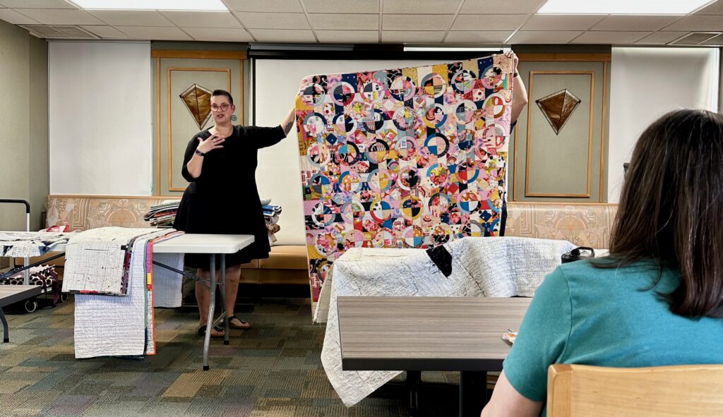 quilter maday delgado shows off a colorful, scrappy quilt