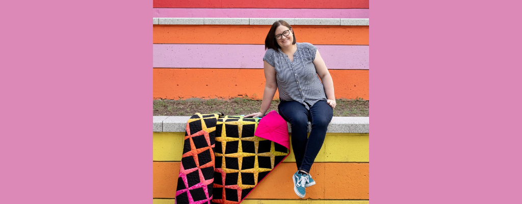 laura hopper in front of a striped wall with a colorful quilt