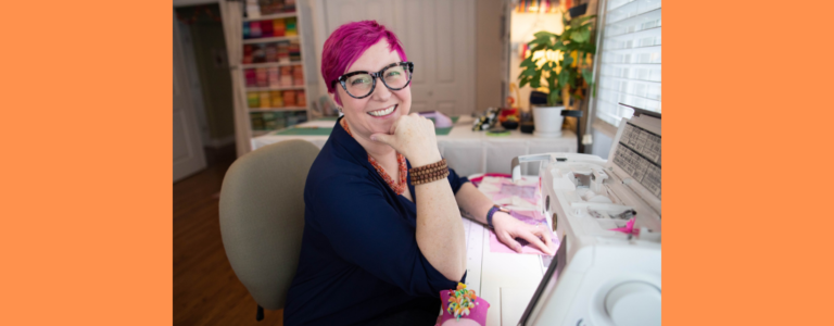 Jenni Grover: a white woman with pink hair and glasses
